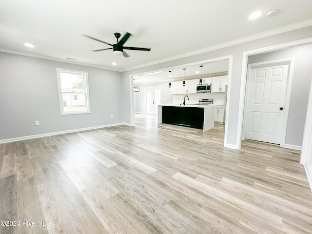 unfurnished living room with light hardwood / wood-style floors, sink, crown molding, and ceiling fan