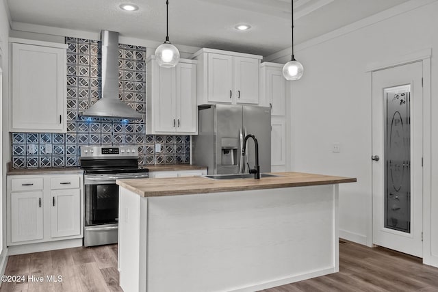 kitchen featuring wall chimney exhaust hood, hanging light fixtures, appliances with stainless steel finishes, and an island with sink