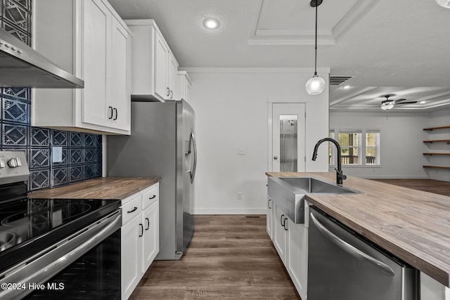 kitchen featuring stainless steel appliances, white cabinetry, wall chimney exhaust hood, and wooden counters