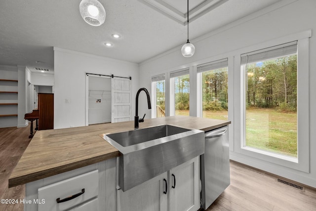 kitchen featuring stainless steel dishwasher, a barn door, a textured ceiling, decorative light fixtures, and white cabinetry