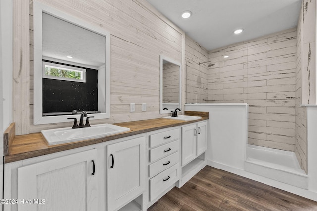 bathroom featuring hardwood / wood-style flooring, vanity, and tiled shower