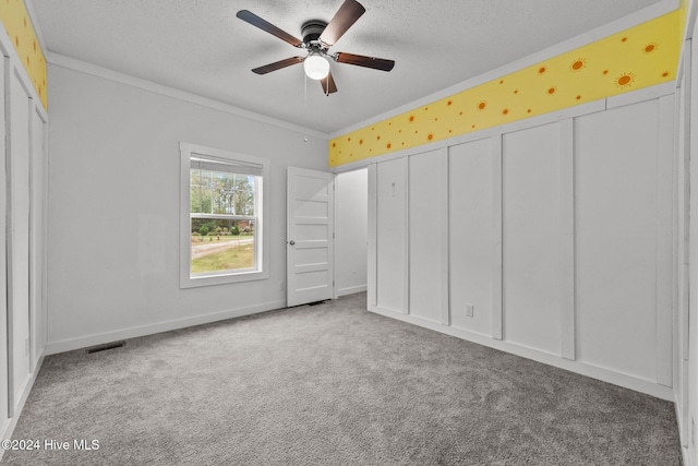 unfurnished bedroom featuring ceiling fan, crown molding, light colored carpet, and a textured ceiling