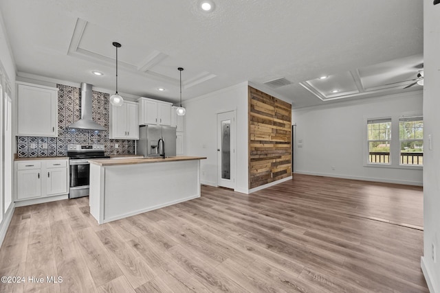 kitchen featuring a kitchen island with sink, white cabinetry, stainless steel appliances, and wall chimney range hood