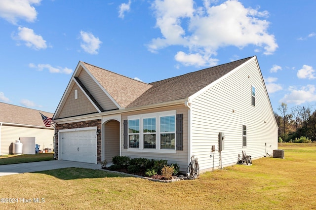 view of front of home featuring a garage, cooling unit, and a front lawn