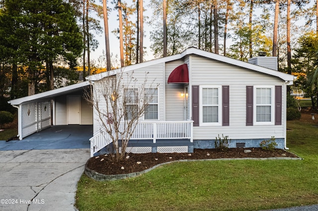 view of front of house featuring covered porch, a front yard, and a carport