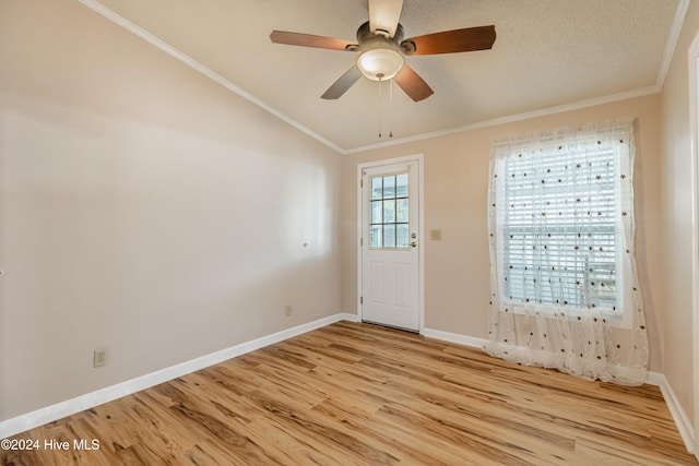 interior space featuring a healthy amount of sunlight, light hardwood / wood-style floors, ornamental molding, and vaulted ceiling