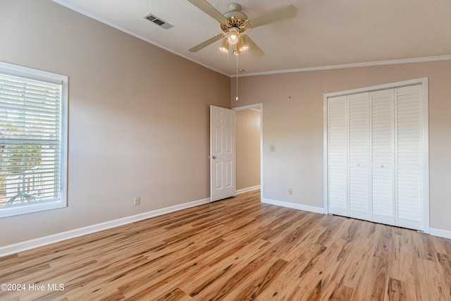 unfurnished bedroom with ceiling fan, light hardwood / wood-style flooring, crown molding, lofted ceiling, and a closet