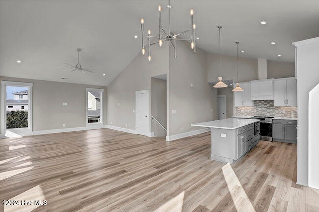 kitchen featuring gray cabinetry, high vaulted ceiling, light hardwood / wood-style floors, decorative light fixtures, and a kitchen island