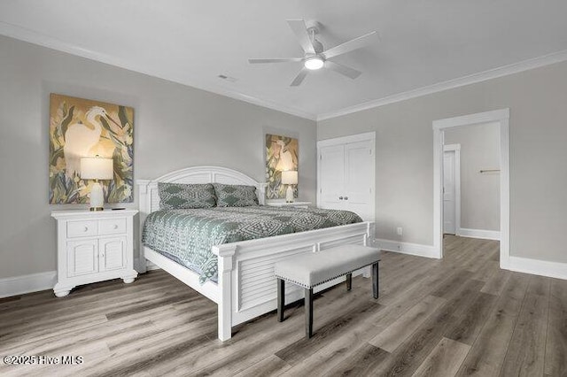 bedroom featuring crown molding, wood finished floors, baseboards, and a closet