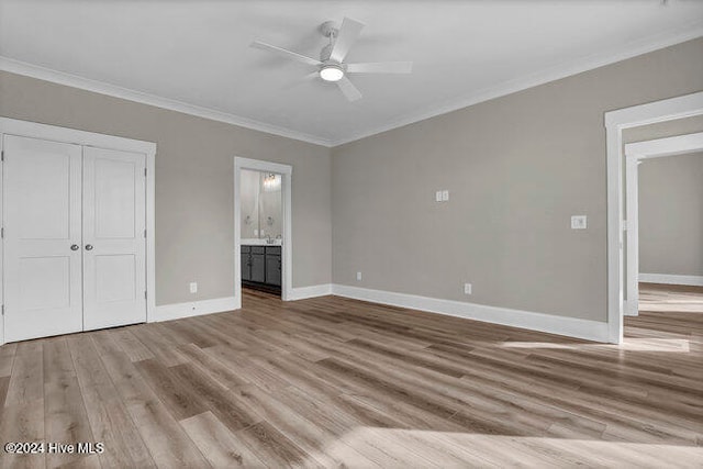 unfurnished bedroom featuring ensuite bathroom, crown molding, ceiling fan, light hardwood / wood-style floors, and a closet