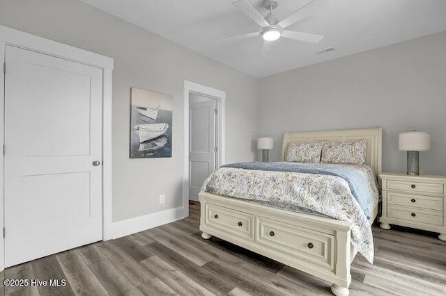 bedroom with ceiling fan, visible vents, baseboards, and wood finished floors