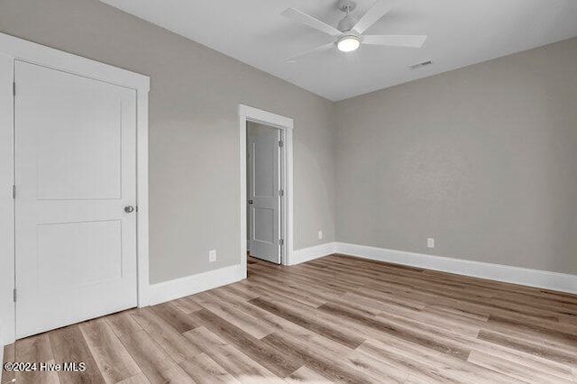 unfurnished bedroom featuring ceiling fan, light hardwood / wood-style floors, and a closet