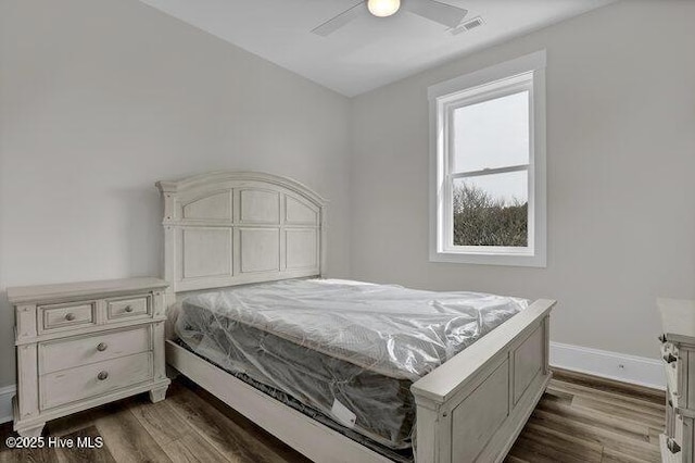 bedroom featuring dark wood-style floors, visible vents, ceiling fan, and baseboards