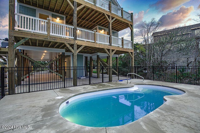 pool at dusk with a patio area