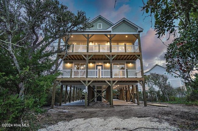 view of front of property featuring a carport, stairway, a balcony, and dirt driveway