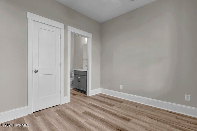 unfurnished bedroom featuring ensuite bathroom and light wood-type flooring