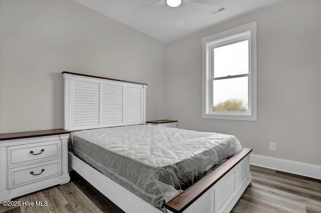 bedroom with visible vents, baseboards, dark wood finished floors, and a ceiling fan