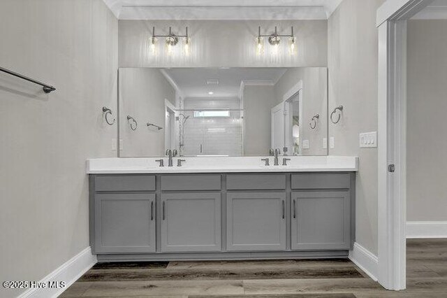 bathroom with hardwood / wood-style floors, vanity, a shower with shower door, and ornamental molding