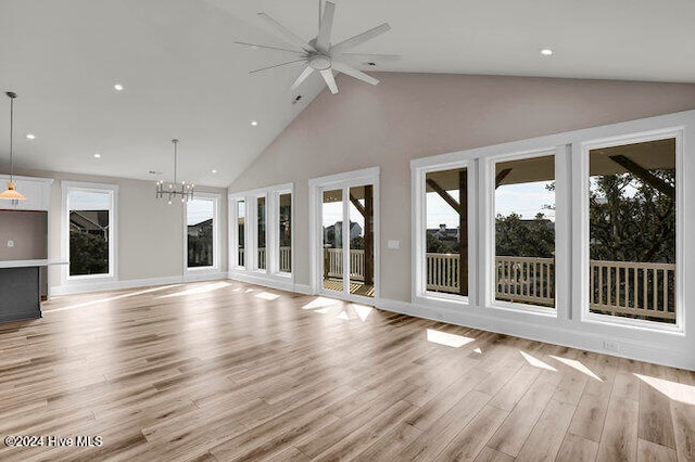 unfurnished living room with ceiling fan with notable chandelier, light wood-type flooring, and high vaulted ceiling