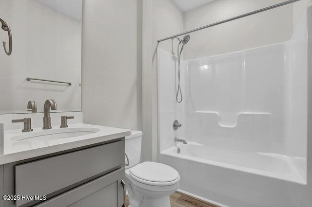 full bath with shower / tub combination, toilet, vanity, and wood finished floors