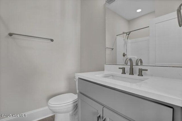 bathroom with visible vents, toilet, baseboards, walk in shower, and vanity