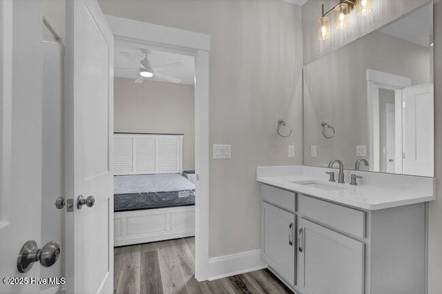 bathroom with vanity, wood finished floors, a ceiling fan, baseboards, and ensuite bath