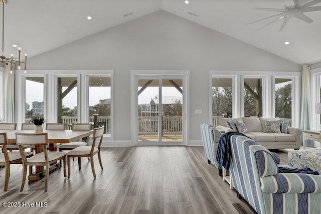 interior space with high vaulted ceiling, ceiling fan with notable chandelier, wood finished floors, recessed lighting, and baseboards