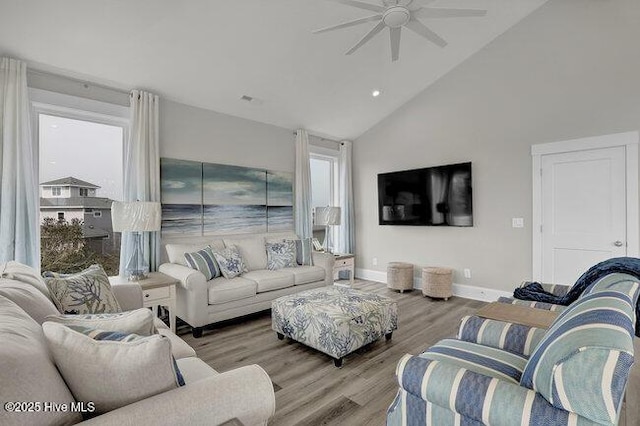 living area with high vaulted ceiling, wood finished floors, baseboards, and ceiling fan