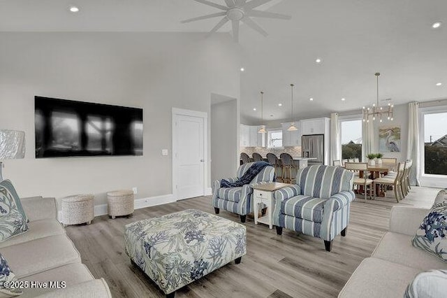 living room featuring recessed lighting, baseboards, light wood-style flooring, and ceiling fan with notable chandelier