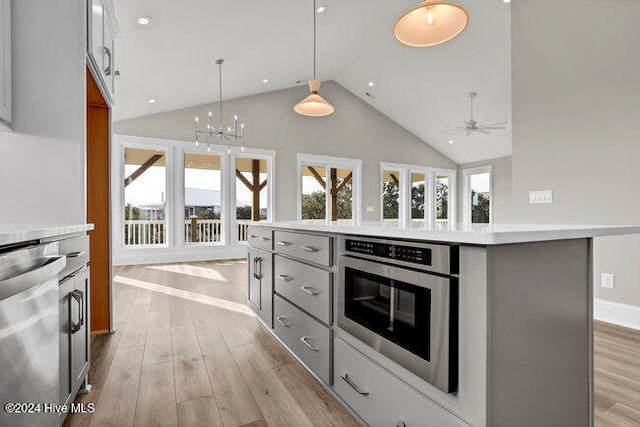 kitchen with a center island, decorative light fixtures, stainless steel appliances, and gray cabinetry