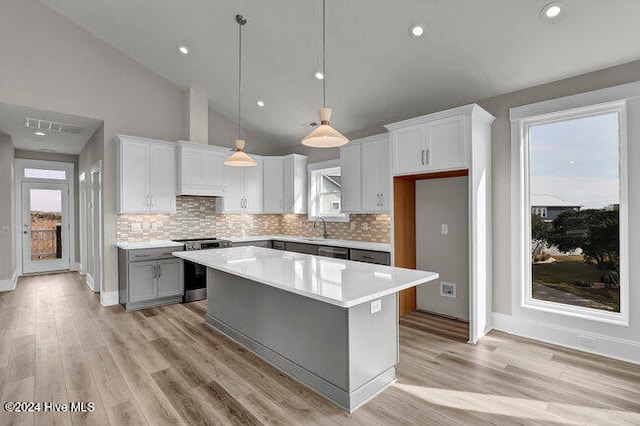 kitchen with white cabinets, decorative light fixtures, a kitchen island, and light hardwood / wood-style flooring