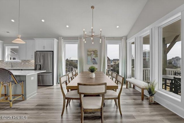 dining area with recessed lighting, a healthy amount of sunlight, vaulted ceiling, and light wood finished floors