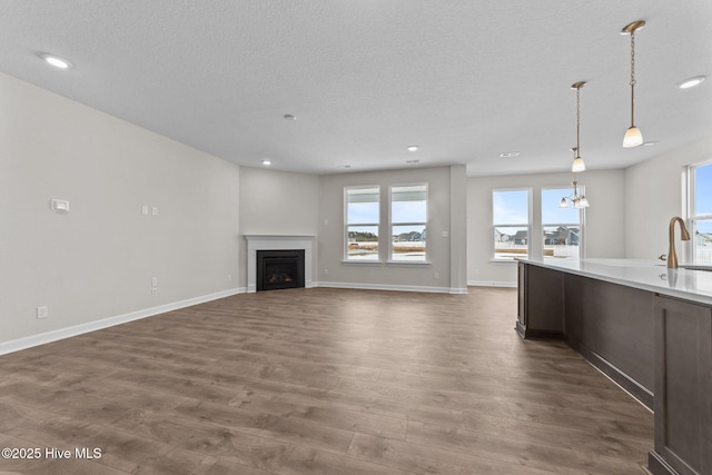 unfurnished living room with recessed lighting, a sink, a textured ceiling, and dark wood-style floors