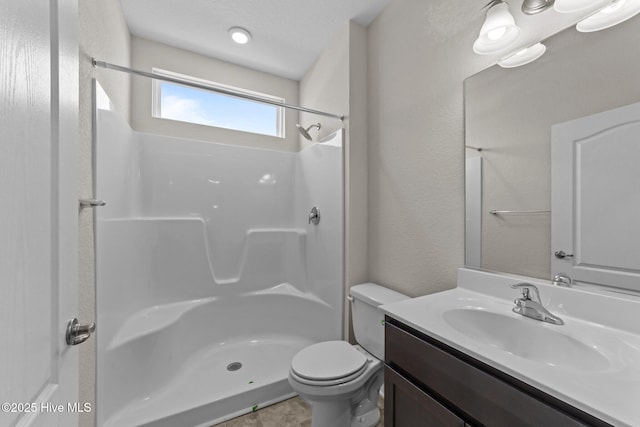 bathroom featuring vanity, walk in shower, and toilet