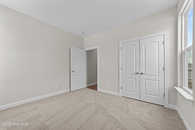unfurnished bedroom featuring carpet floors, baseboards, and a closet