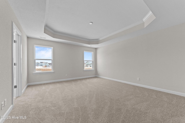 unfurnished room featuring baseboards, ornamental molding, a raised ceiling, and carpet