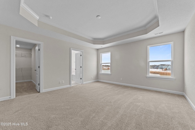 unfurnished bedroom with crown molding, carpet flooring, baseboards, and a spacious closet