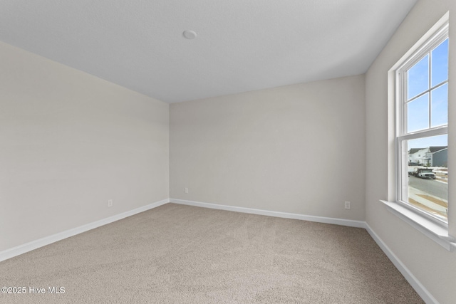 carpeted empty room featuring baseboards