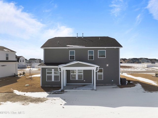 snow covered rear of property with a residential view and cooling unit