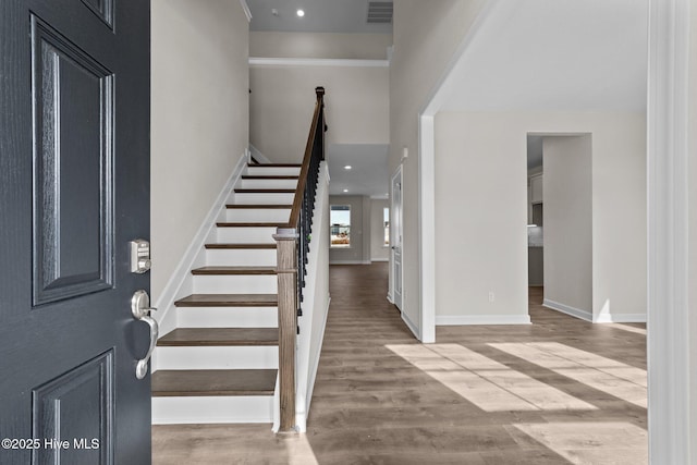 foyer with visible vents, stairs, wood finished floors, baseboards, and recessed lighting