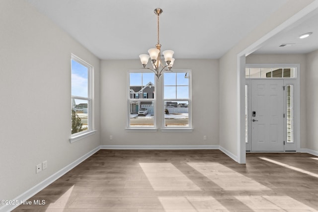 foyer entrance featuring baseboards, a notable chandelier, and light wood-style flooring