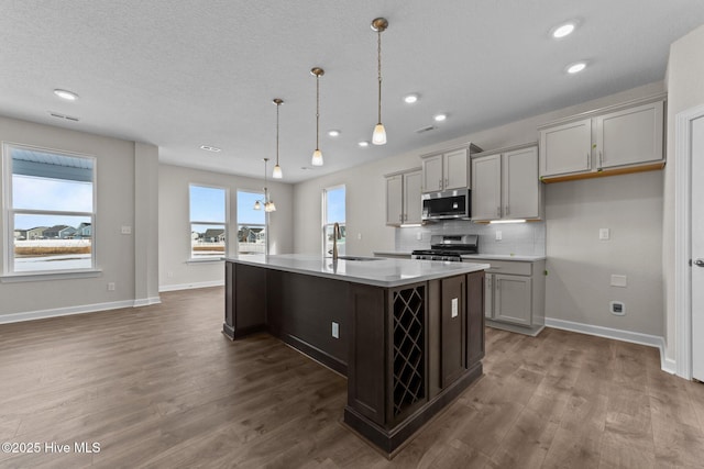 kitchen with recessed lighting, dark wood finished floors, an island with sink, and stainless steel appliances