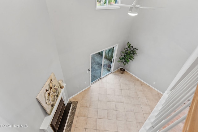 unfurnished living room with a high ceiling, light tile patterned floors, and ceiling fan