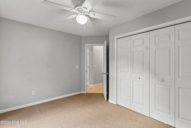 unfurnished bedroom featuring ceiling fan, light carpet, a closet, and a textured ceiling