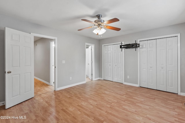 unfurnished bedroom with ceiling fan, multiple closets, and light wood-type flooring