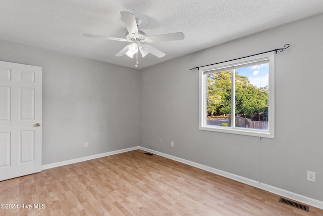 spare room with a textured ceiling, light wood-type flooring, and ceiling fan