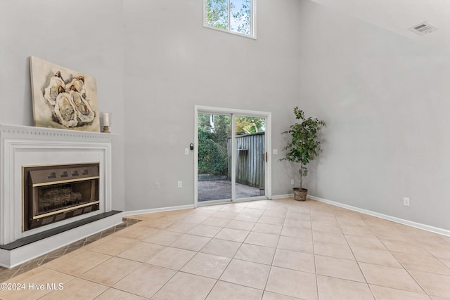 unfurnished living room with a towering ceiling and light tile patterned floors