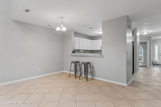 kitchen with white cabinetry, kitchen peninsula, light tile patterned floors, an inviting chandelier, and pendant lighting