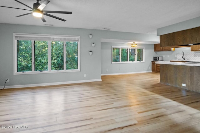 kitchen featuring light hardwood / wood-style floors, ceiling fan, plenty of natural light, and backsplash