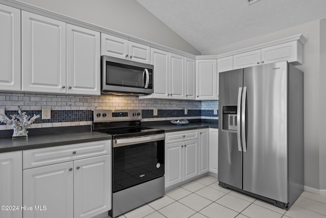 kitchen featuring white cabinetry, dark countertops, lofted ceiling, and appliances with stainless steel finishes